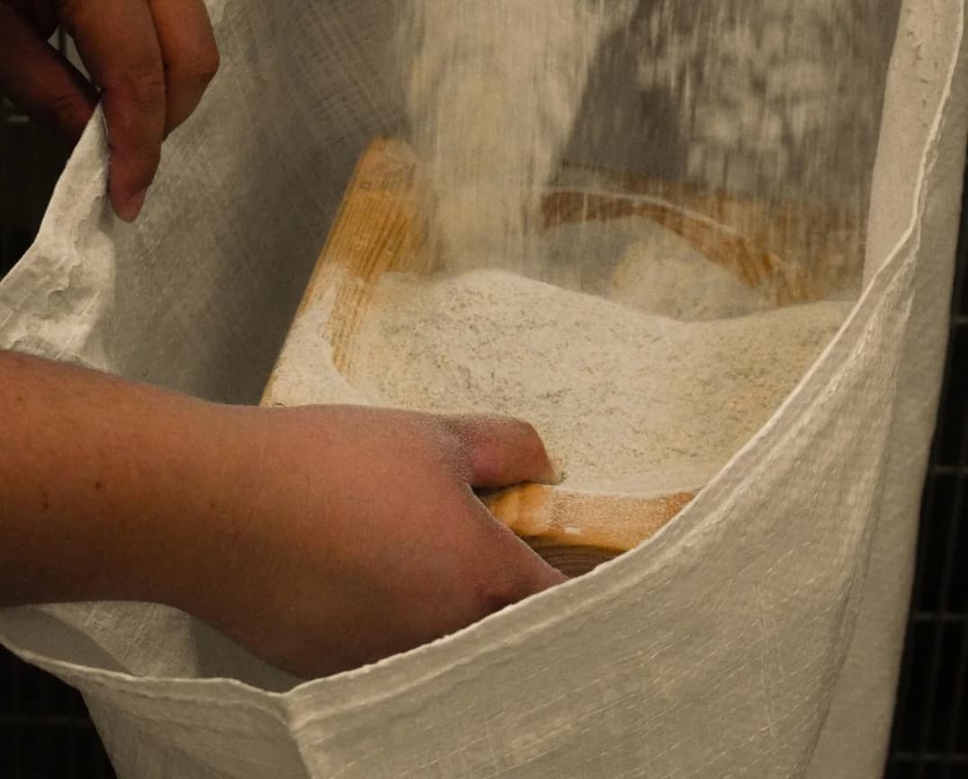 Fresh flour being gathered into a cloth sack